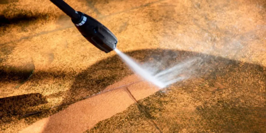 Pressure washer cleaning dirt and stains from a paved area.